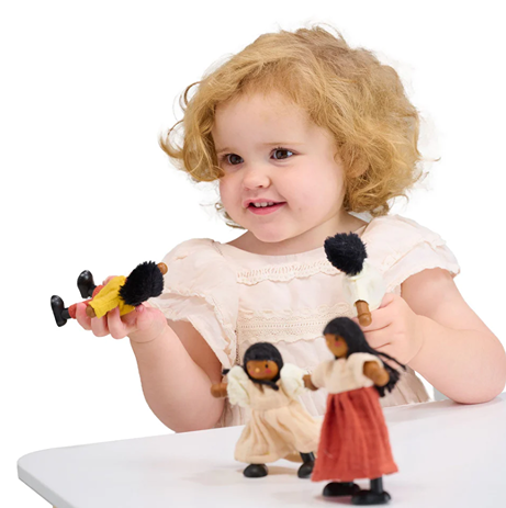 Toddler playing with handcrafted dolls dressed in colorful fabric showcasing a charming family scene