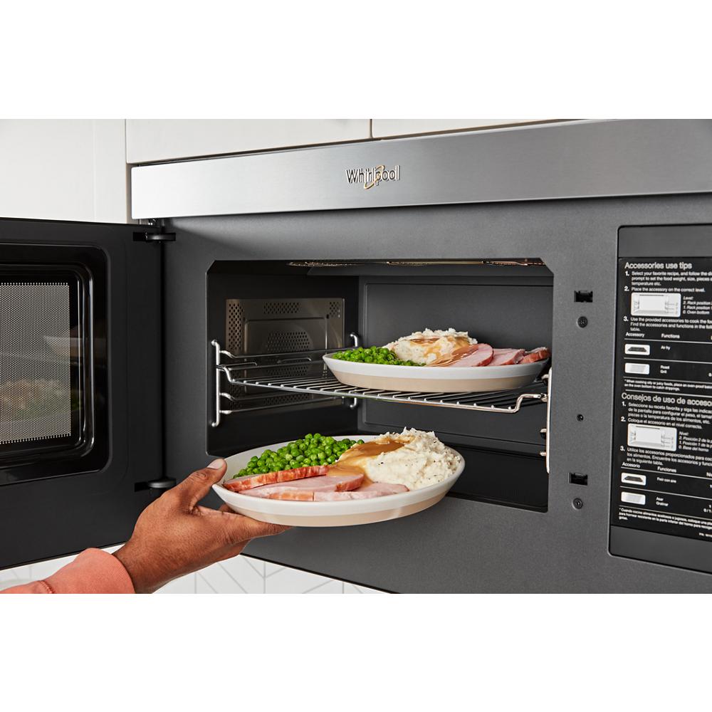 Open Whirlpool air fry microwave with two plates of food inside in modern kitchen appliances setting