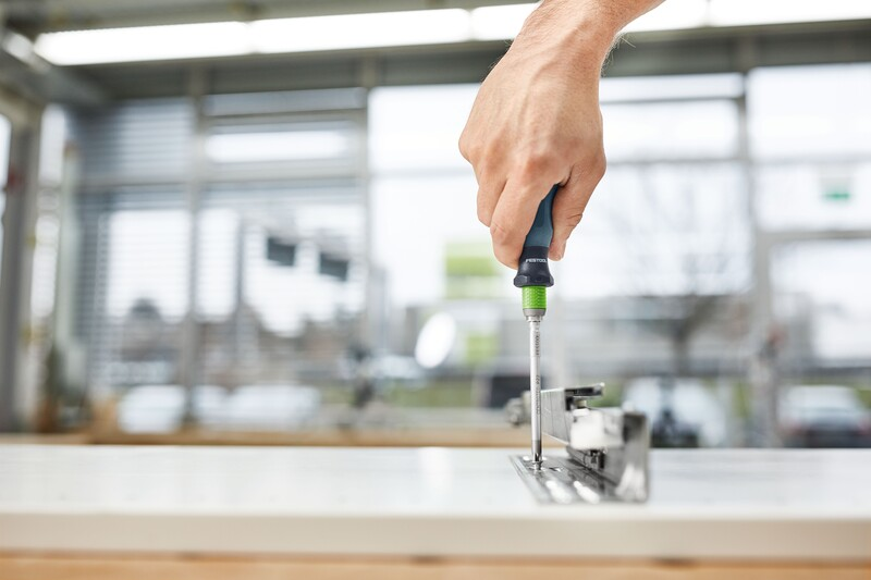 Hand using a screwdriver with green handle tightening a fastener in a home improvement workshop setting