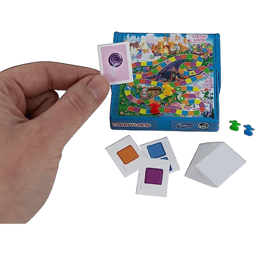 Hand holding a miniature game card above a small colorful Candyland board game with playing pieces and cards
