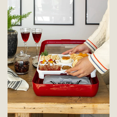 White segmented tray insert organizing assorted appetizers inside a red storage container on wooden table