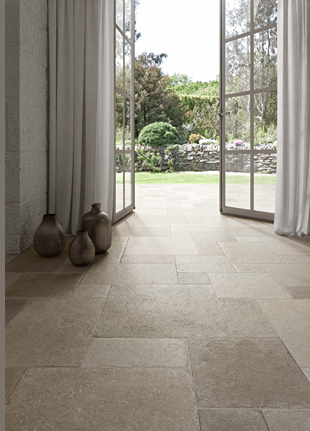 Indoor flooring with matte tufo stone field tiles extending to an outdoor patio with garden views in home improvement collections