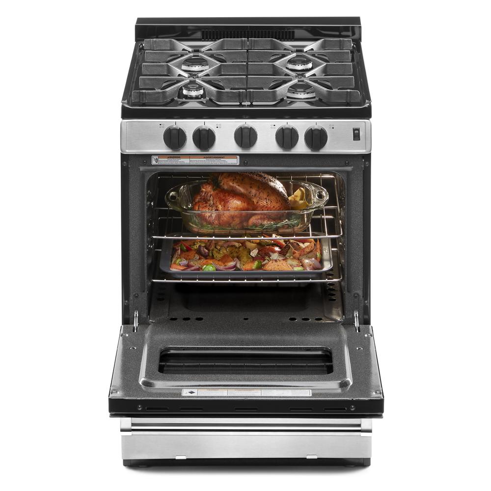 Stainless steel gas range with four burners and oven open showing cooked turkey and roasted vegetables inside