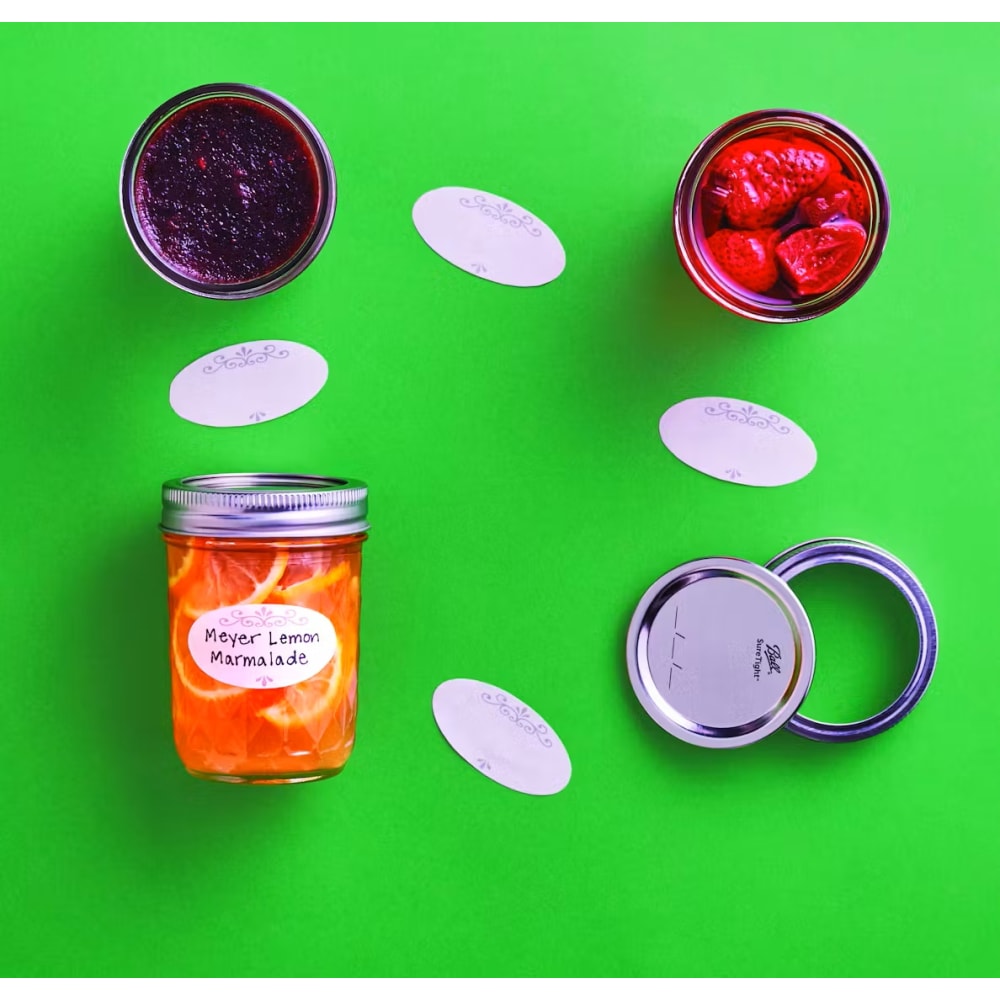 Glass jars with dissolved jar labels used for organizing homemade preserves on bright green surface