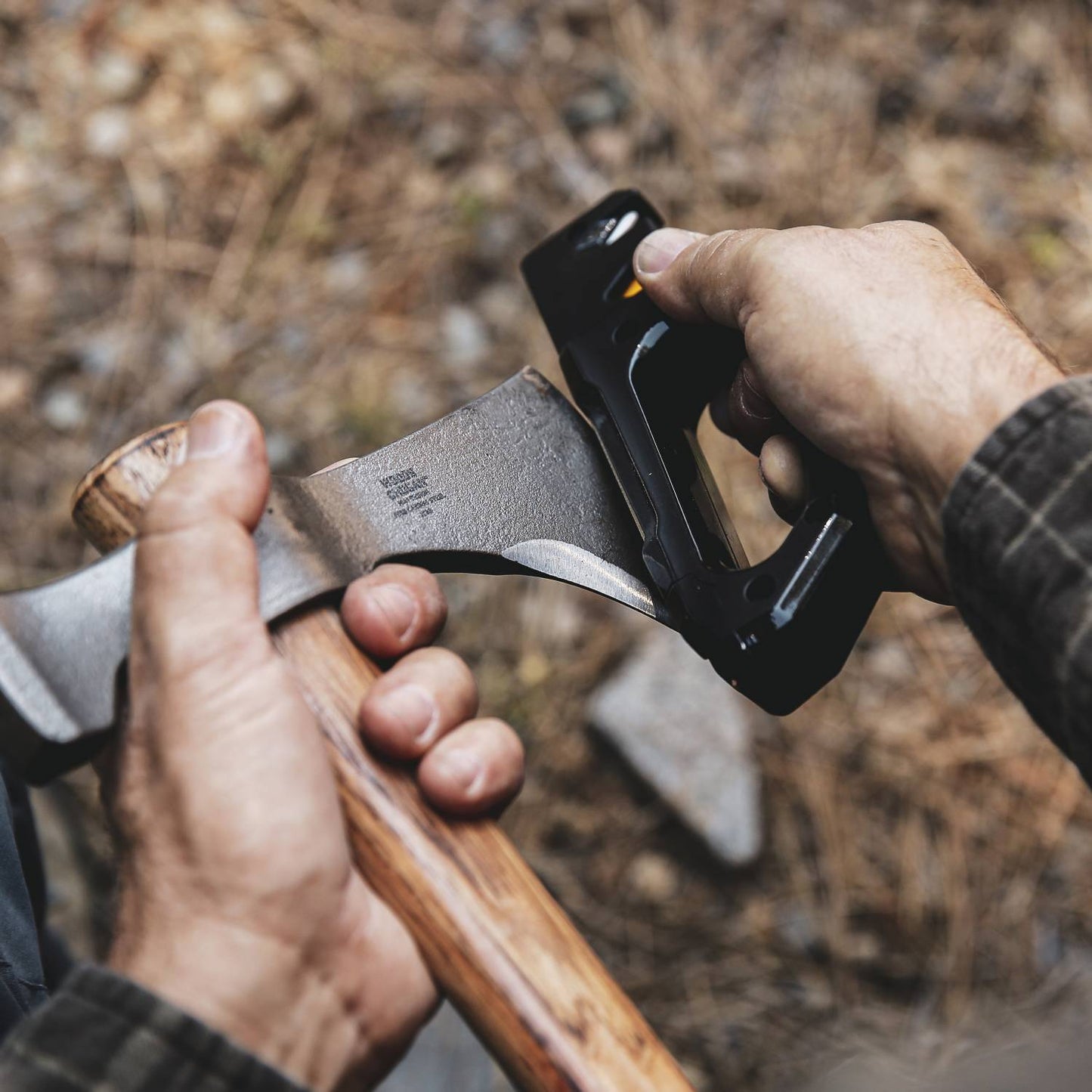 Person sharpening axe blade with black and yellow Work Sharp Pivot Pro for outdoor tool maintenance and home improvement