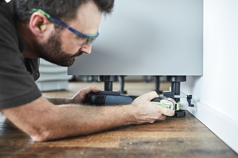 Man wearing safety glasses using a Festool depth stop set with an oscillating multi-tool on hardwood flooring at Hartville Hardware
