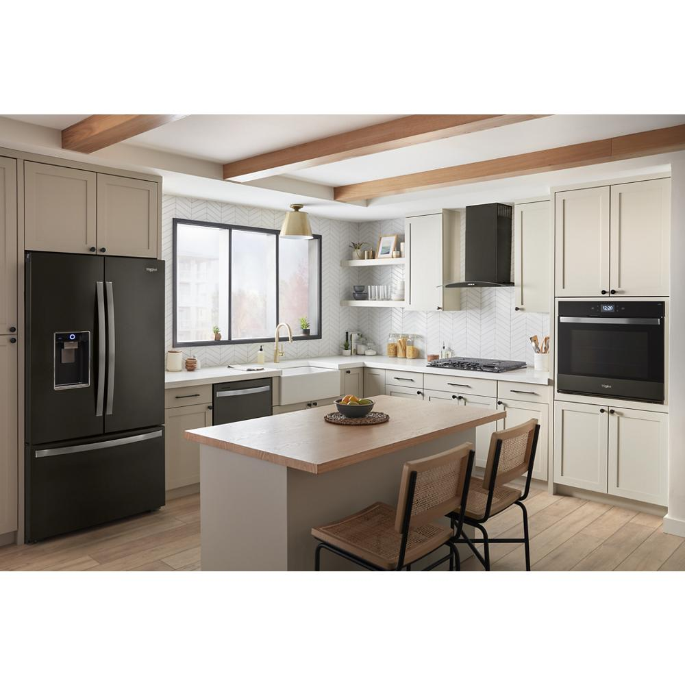 Modern kitchen with a black concave glass wall mount range hood, beige cabinetry, island seating, and stainless steel appliances