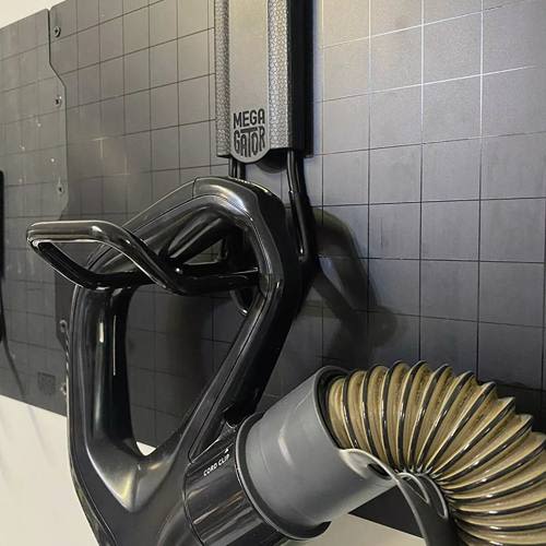 Black closed magnetic hook with wide curved arm holding vacuum hose for tools and home improvement storage