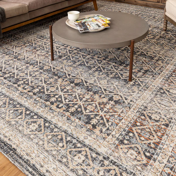 Slate-toned rug with intricate geometric and floral patterns beneath a round coffee table in a cozy living space