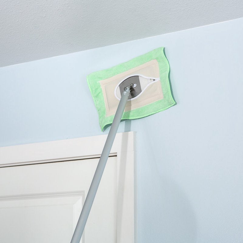 Green and beige microfiber mop head attached to pole cleaning upper wall and ceiling in home setting