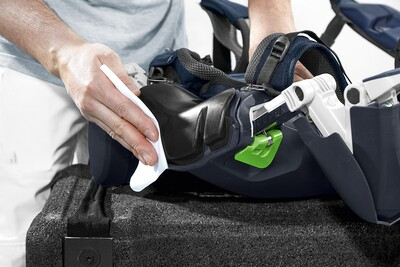 Person cleaning black ergonomic headrest with white cloth on workbench in Festool power tool accessories collection