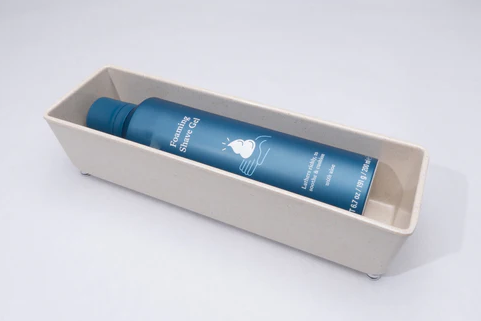 Rectangular beige bamboo melamine tray holding a blue bottle, ideal for countertop storage and organization.