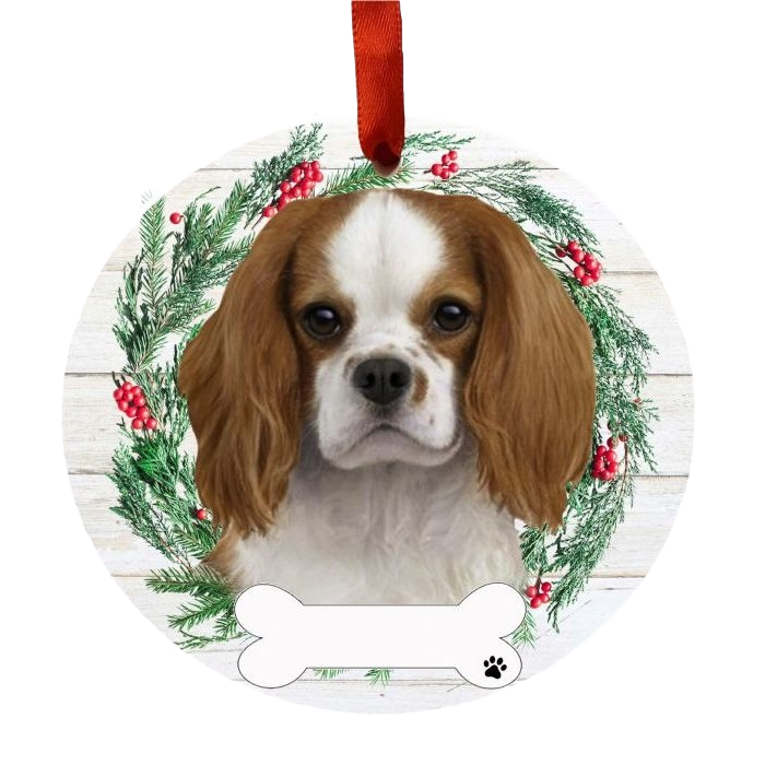 Round Christmas ornament with King Charles Cavalier dog face and festive green wreath with red berries and red ribbon.