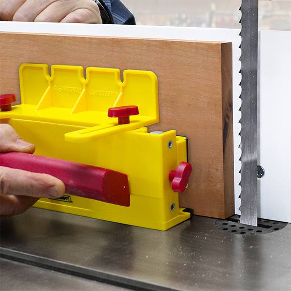 Yellow and red push block securing wood against saw blade for safe, precise cutting in tools and home improvement projects