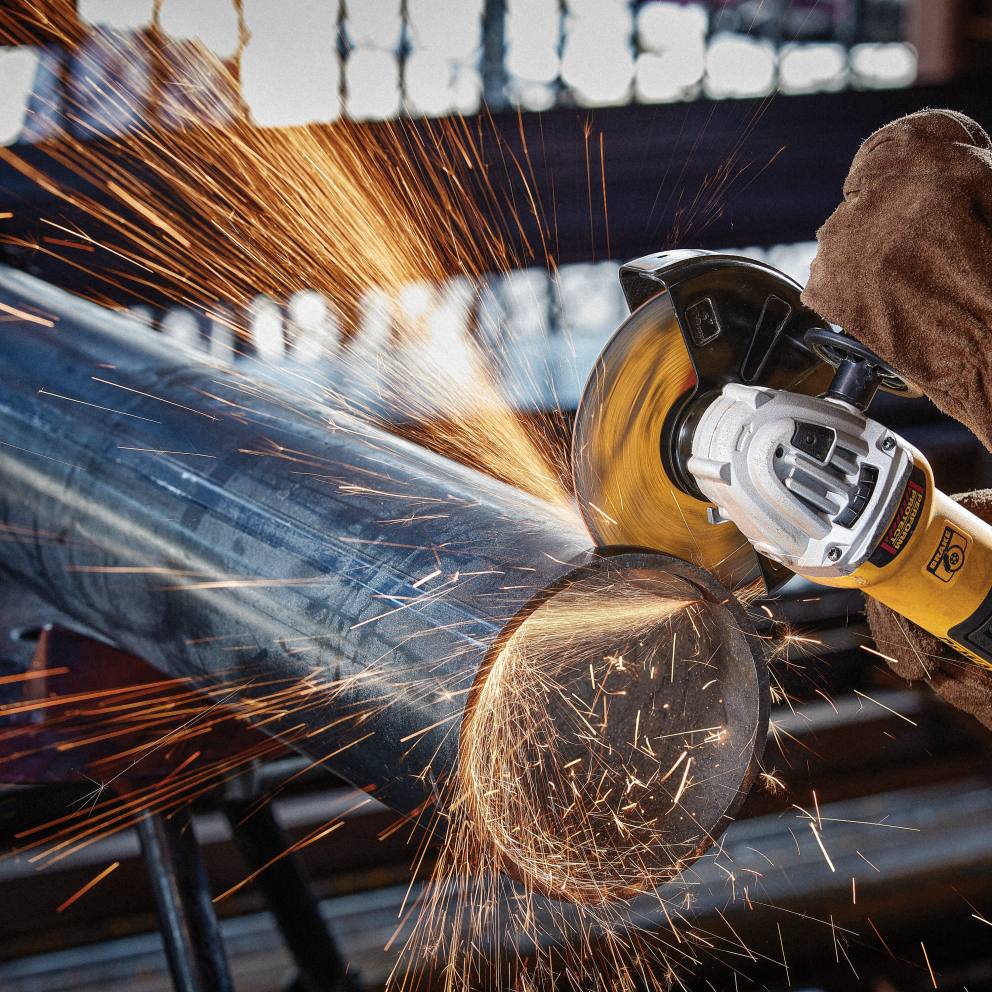 Metal cutting wheel on power grinder generating sparks while cutting steel pipe for tools and home improvement use