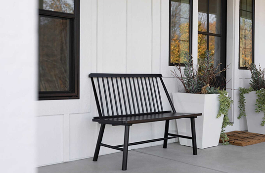 Black Indonesian hardwood bench with vertical spindle backrest on porch for patio furniture and outdoor living decor