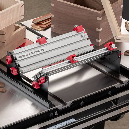 Precision aluminum spline jig with red adjustment knobs mounted on table saw for detailed woodworking joinery cuts