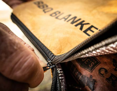 Close-up of a tan insulated BBQ blanket with black zipper used for heat retention during grilling tasks