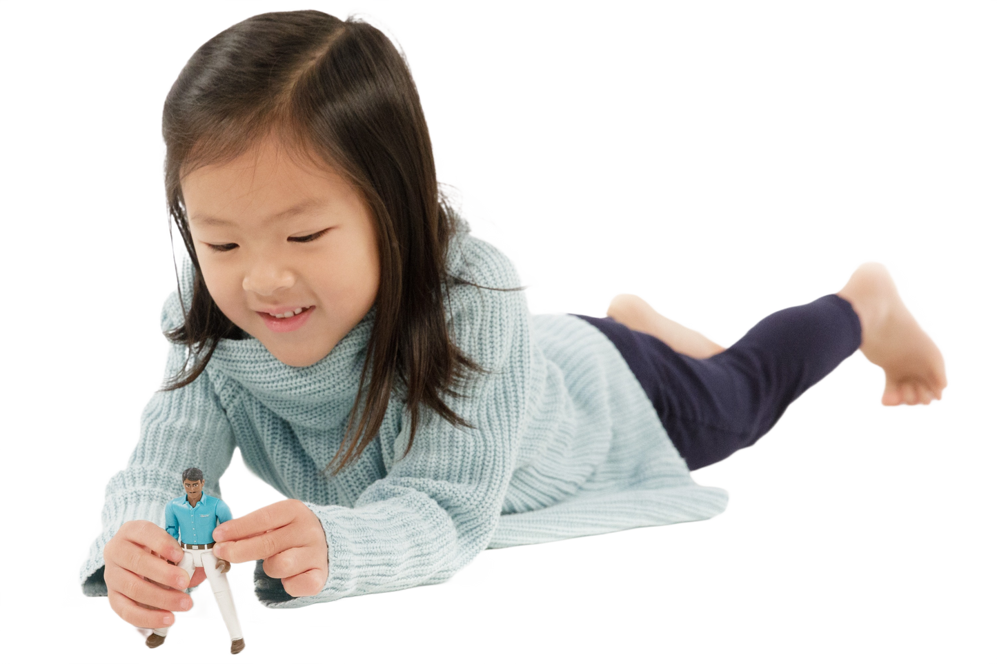 Young girl wearing light blue sweater and dark pants playing with action figure in teal shirt and white jeans