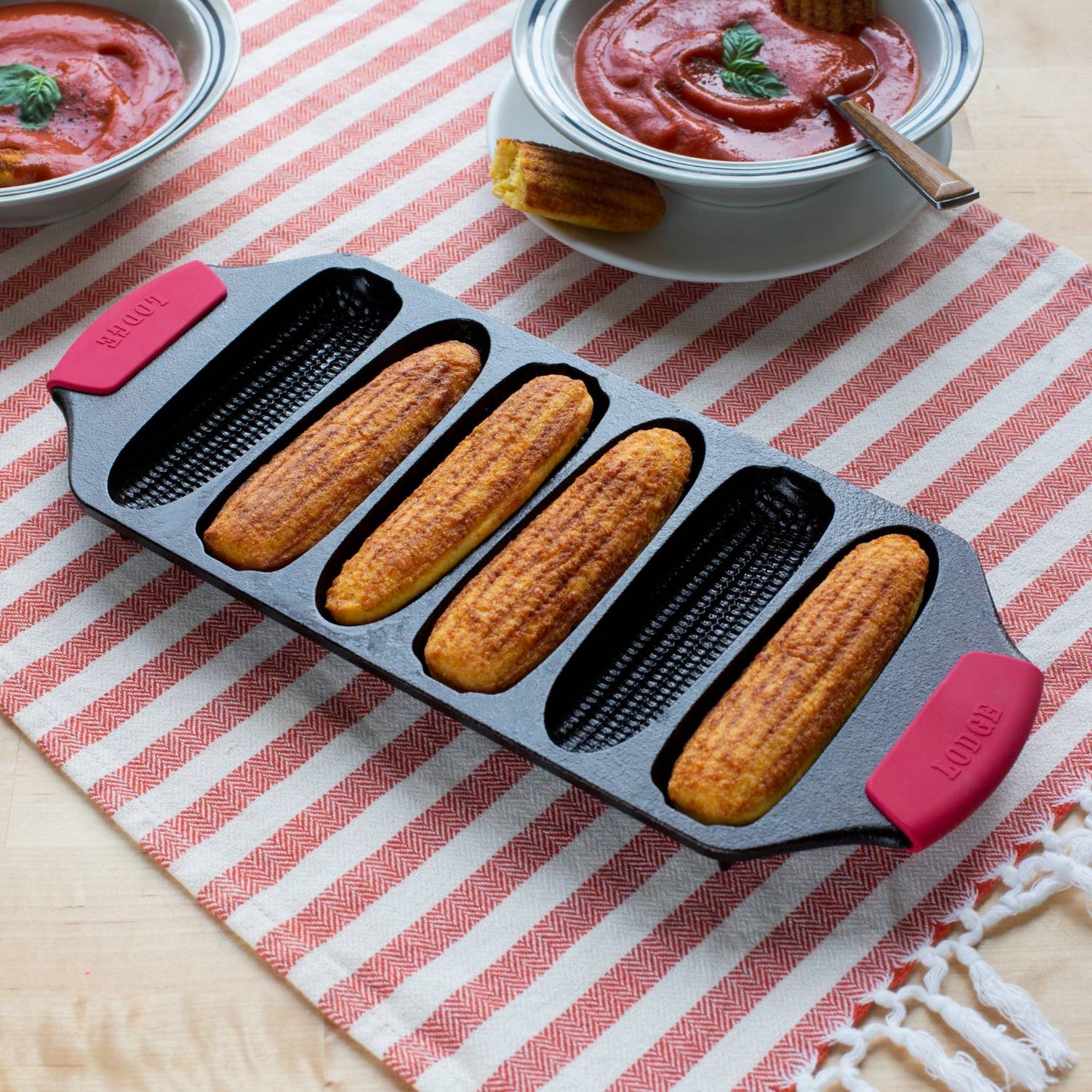 Cast iron cornstick pan with red silicone handle grips and six ear-shaped molds in kitchenware collections