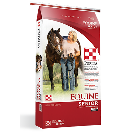 Red and white bag of Purina Equine Senior horse feed with image of woman walking a horse on grass background