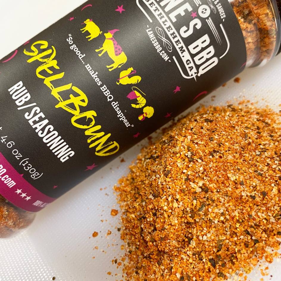 Close-up of bold, flavorful seasoning rub spilling beside a black bottle, perfect for grilling and outdoor cooking collections