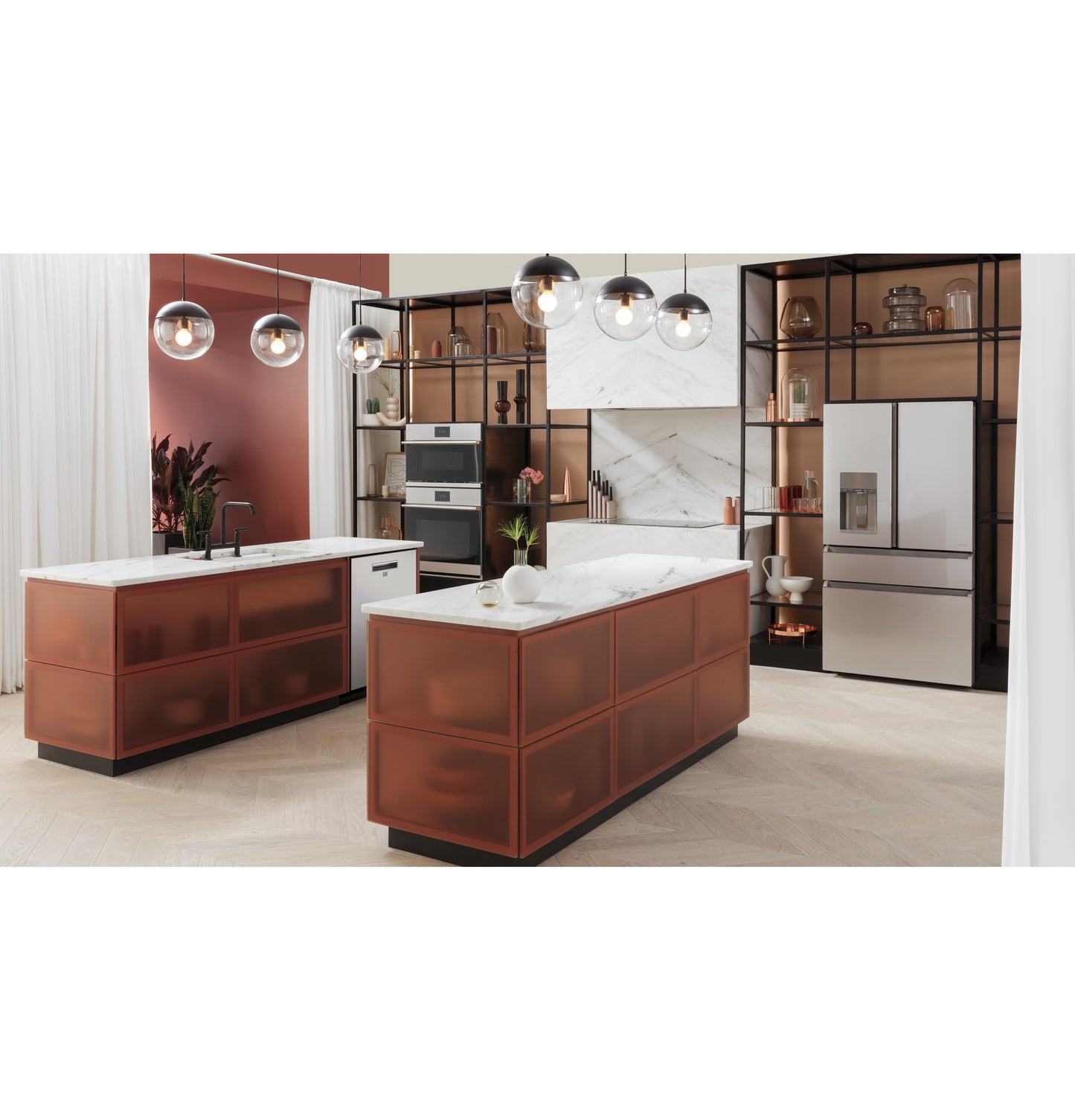 Modern kitchen with two rust-colored island counters featuring white marble tops, smart appliances, and glass pendant lights