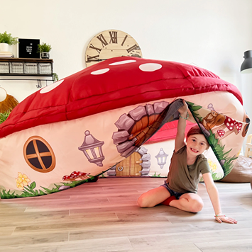 Child sitting inside a red and white mushroom-shaped inflatable playhouse with decorative details on wood floor