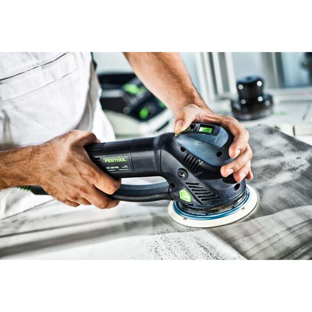 Hands operating Festool power sander with hard sanding pad for smoothing wood surface in home improvement setting