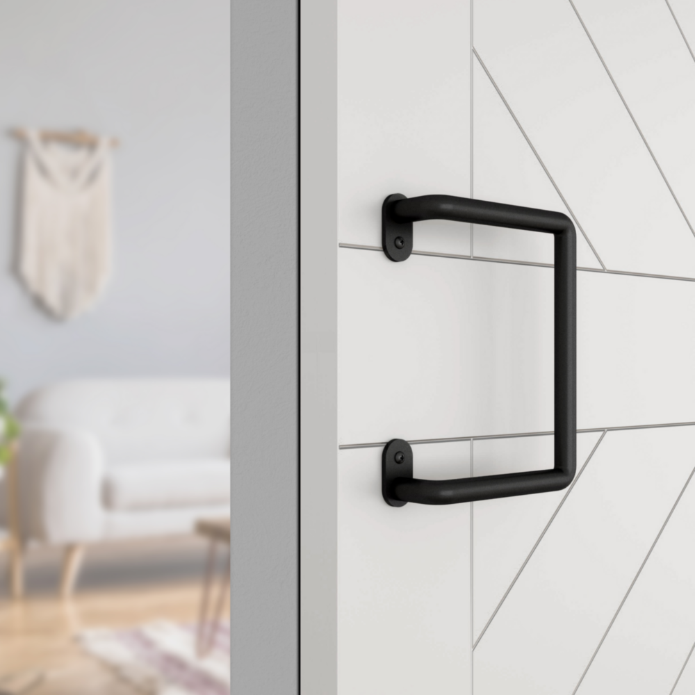 Matte black interior barn door pull handle mounted on white wood door with modern diagonal panel design under $50 hardware