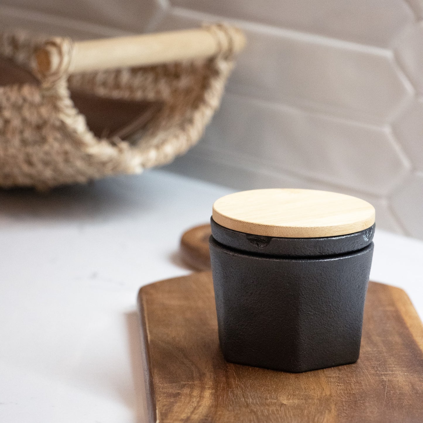Compact cast iron spice grinder with smooth light wood lid on wooden board in kitchenware and kitchen gadgets collection