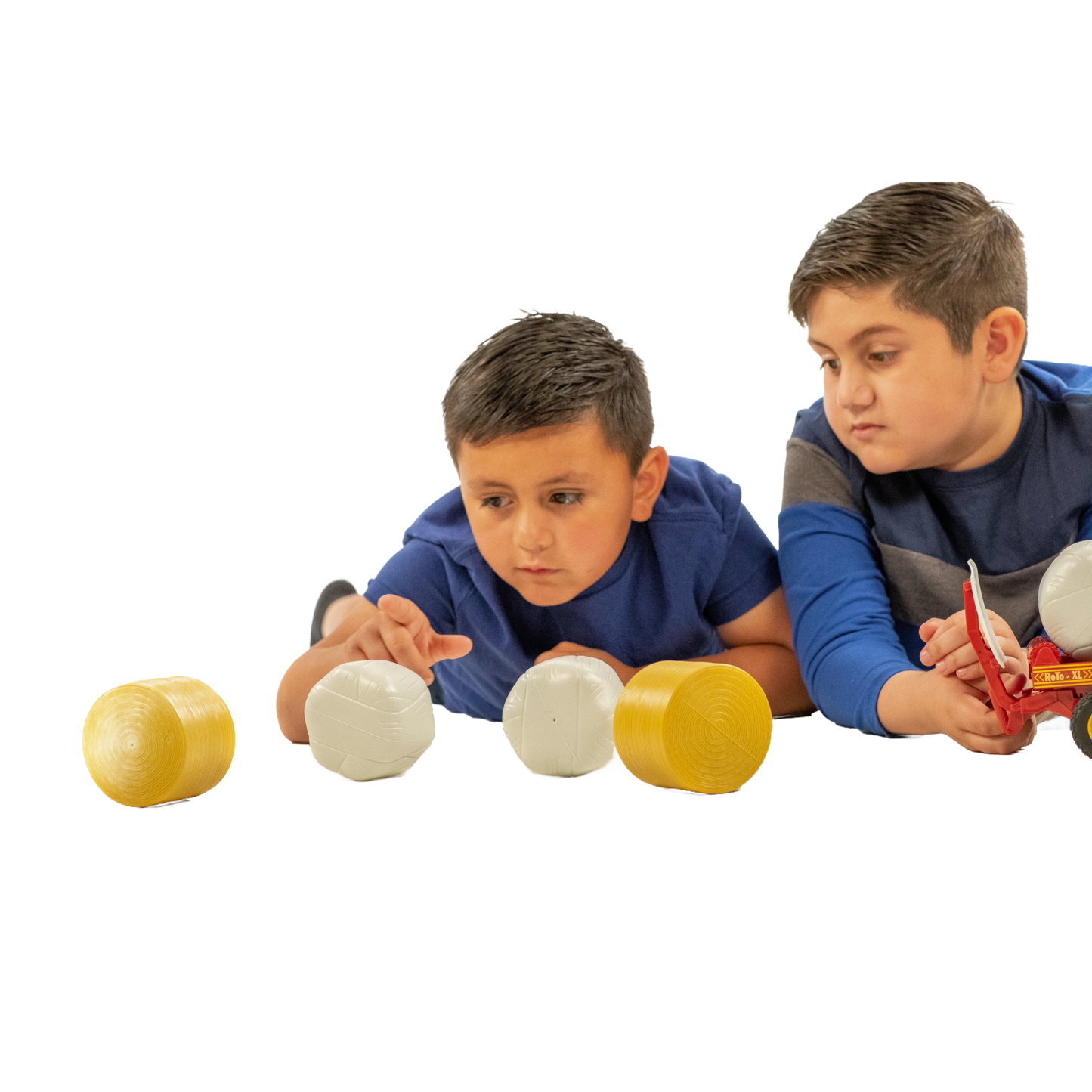 Two boys playing with a set of four toy round bales in yellow and white from Bruder Toys collection under $50