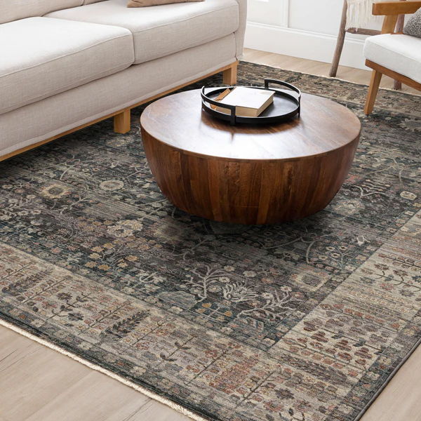 Denim blue rug with vintage-inspired floral and geometric motifs under a round wooden coffee table in modern living room