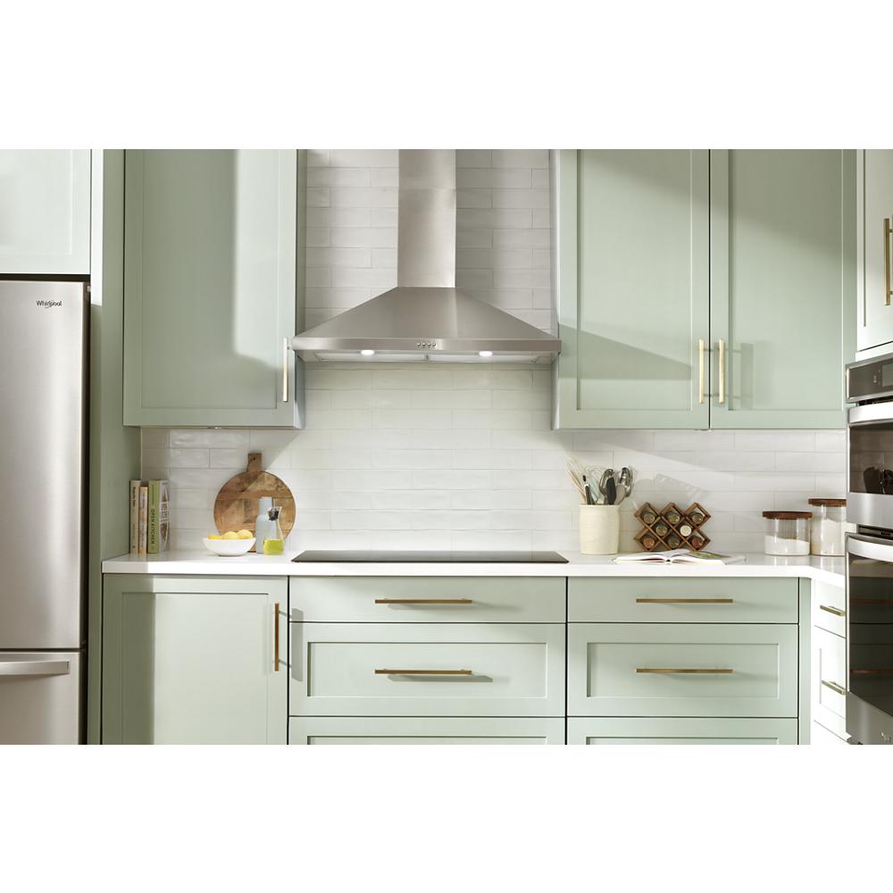 Modern kitchen with 36" stainless steel chimney range hood above cooktop, mint green cabinetry, and brass hardware handles