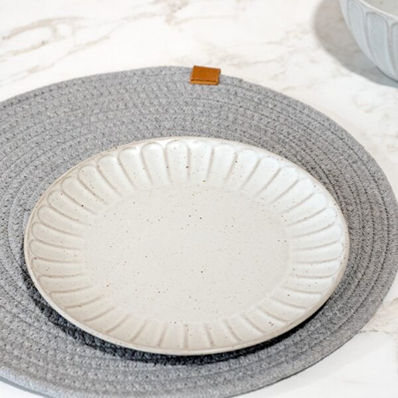 White ceramic stoneware side plate with subtle textured rim on gray woven placemat for home use