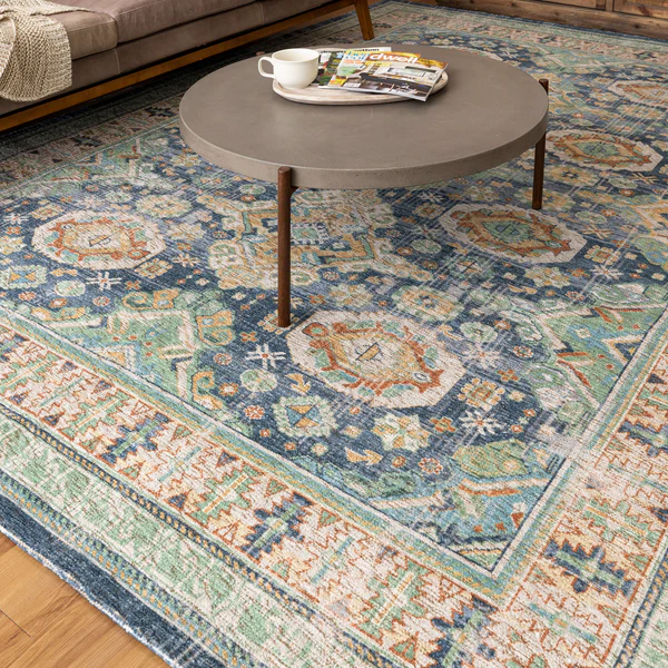 Blue and green patterned area rug with intricate geometric and floral motifs under a round coffee table in a living room