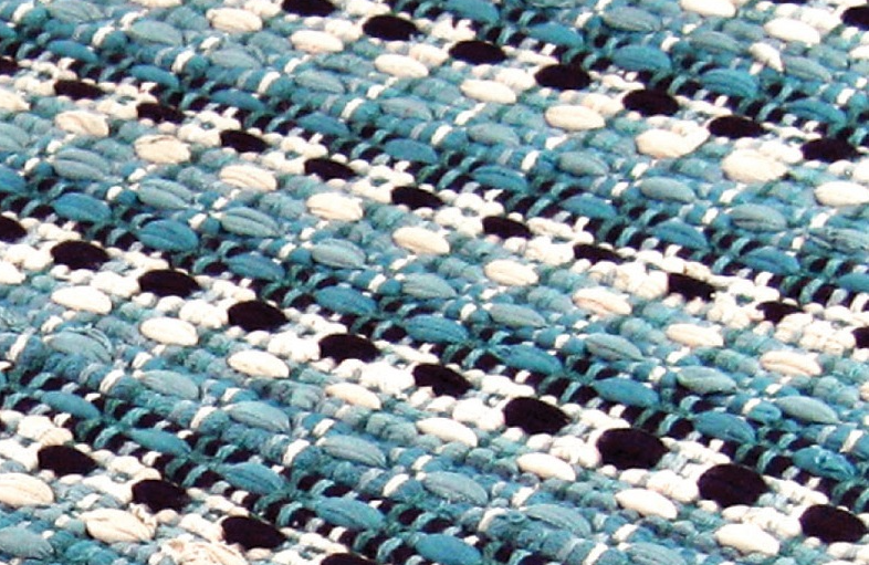 Close-up of textured woven fabric in blue, white, and black creating a handcrafted rag rug pattern.