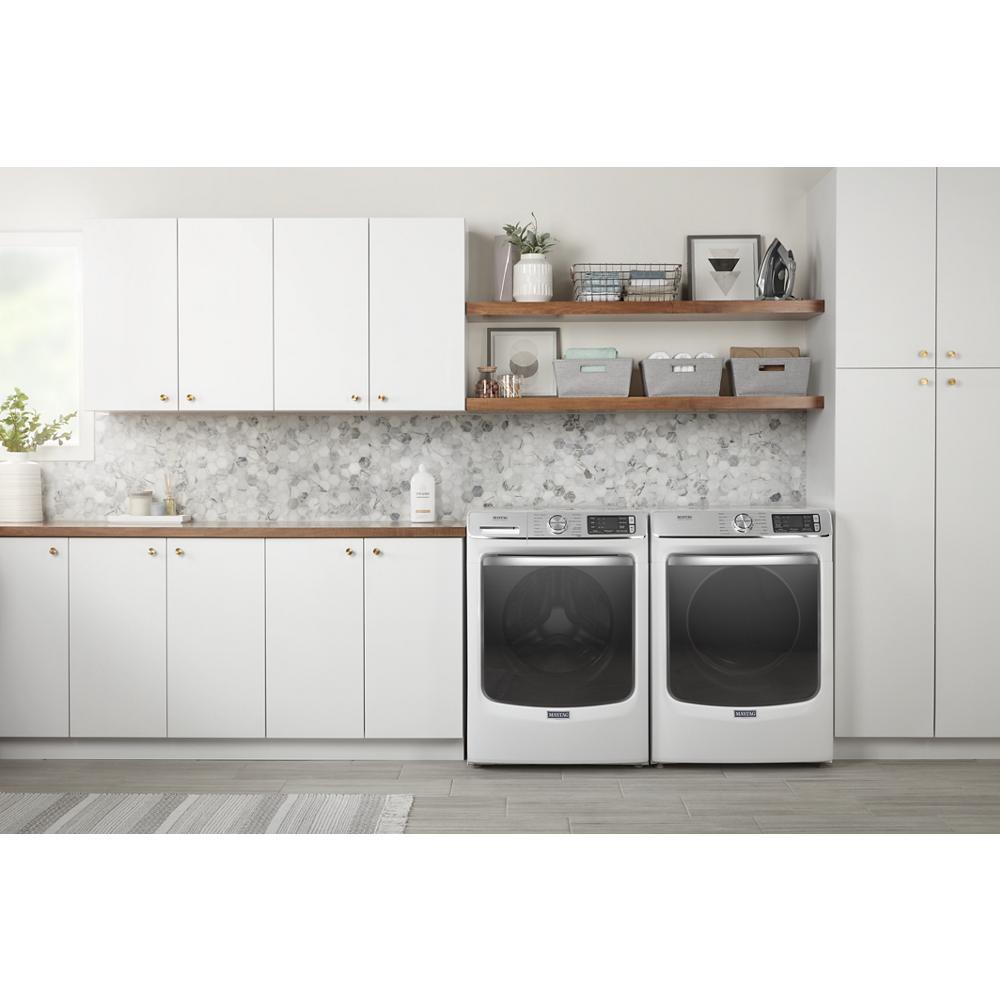 Modern laundry room featuring white front load washer and dryer with wood shelf and white cabinetry in appliances collection