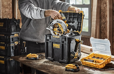 Person placing cordless circular saw into a deep compact DEWALT toolbox on a workshop table for tool storage