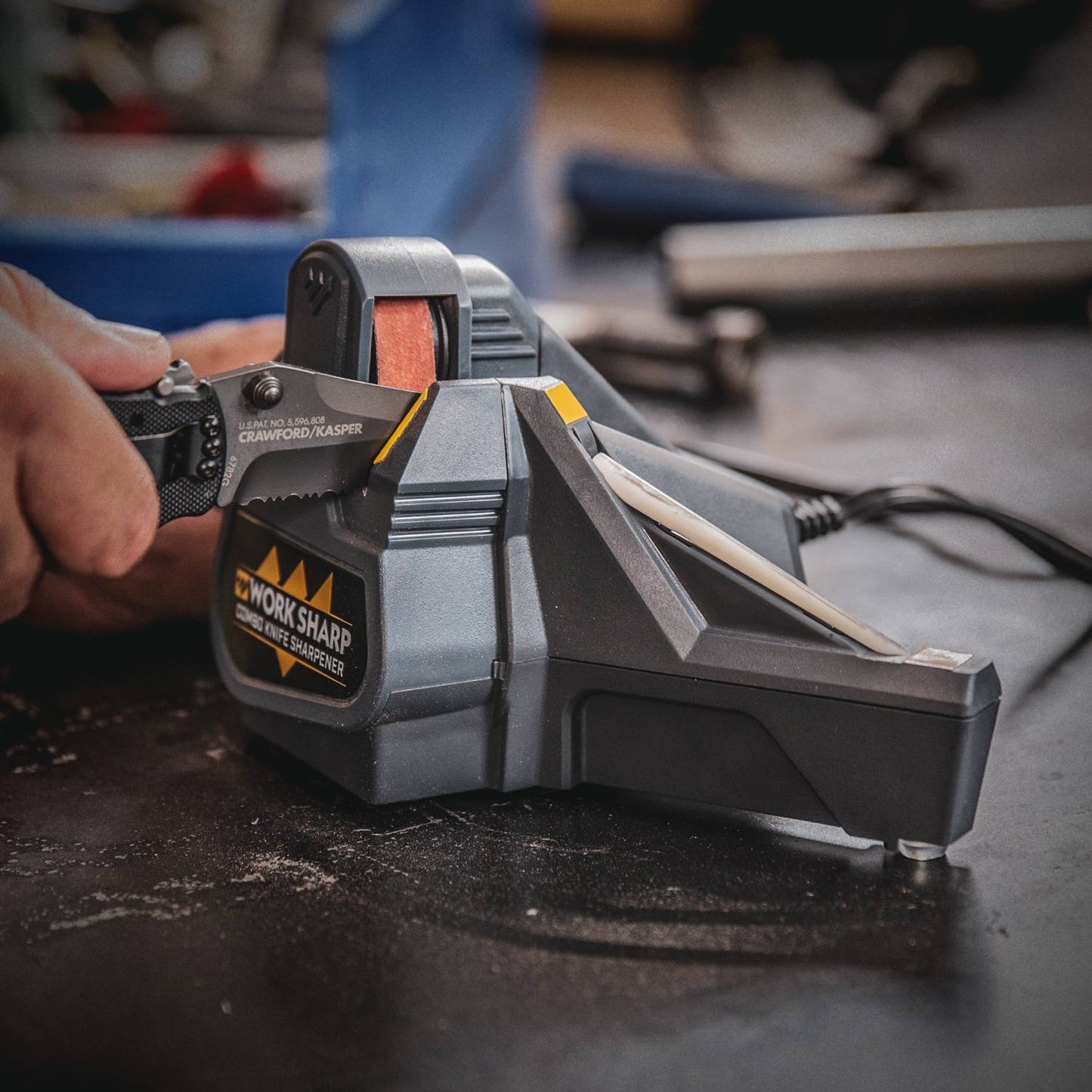 Person sharpening a serrated knife on a black and yellow electric combo sharpener from woodworking tools collection