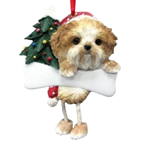 Tan Shih Tzu dog ornament with dangling legs holding large white bone and decorated Christmas tree background