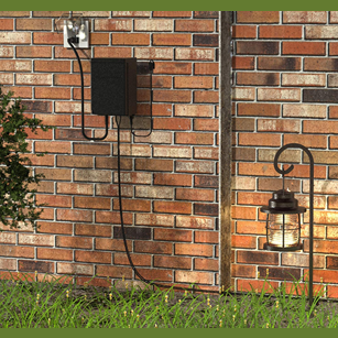 Black outdoor low voltage transformer mounted on brick wall powering landscape lamp in home improvement setting