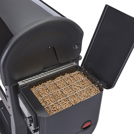 Close-up of an open pellet hopper filled with wood pellets on a black pellet grill, designed for efficient fuel feeding in outdoor cooking.