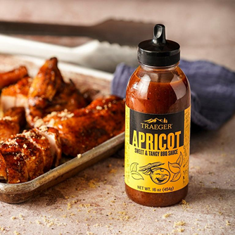 16 oz bottle of Traeger Apricot sweet and tangy BBQ sauce with tray of glazed chicken wings nearby