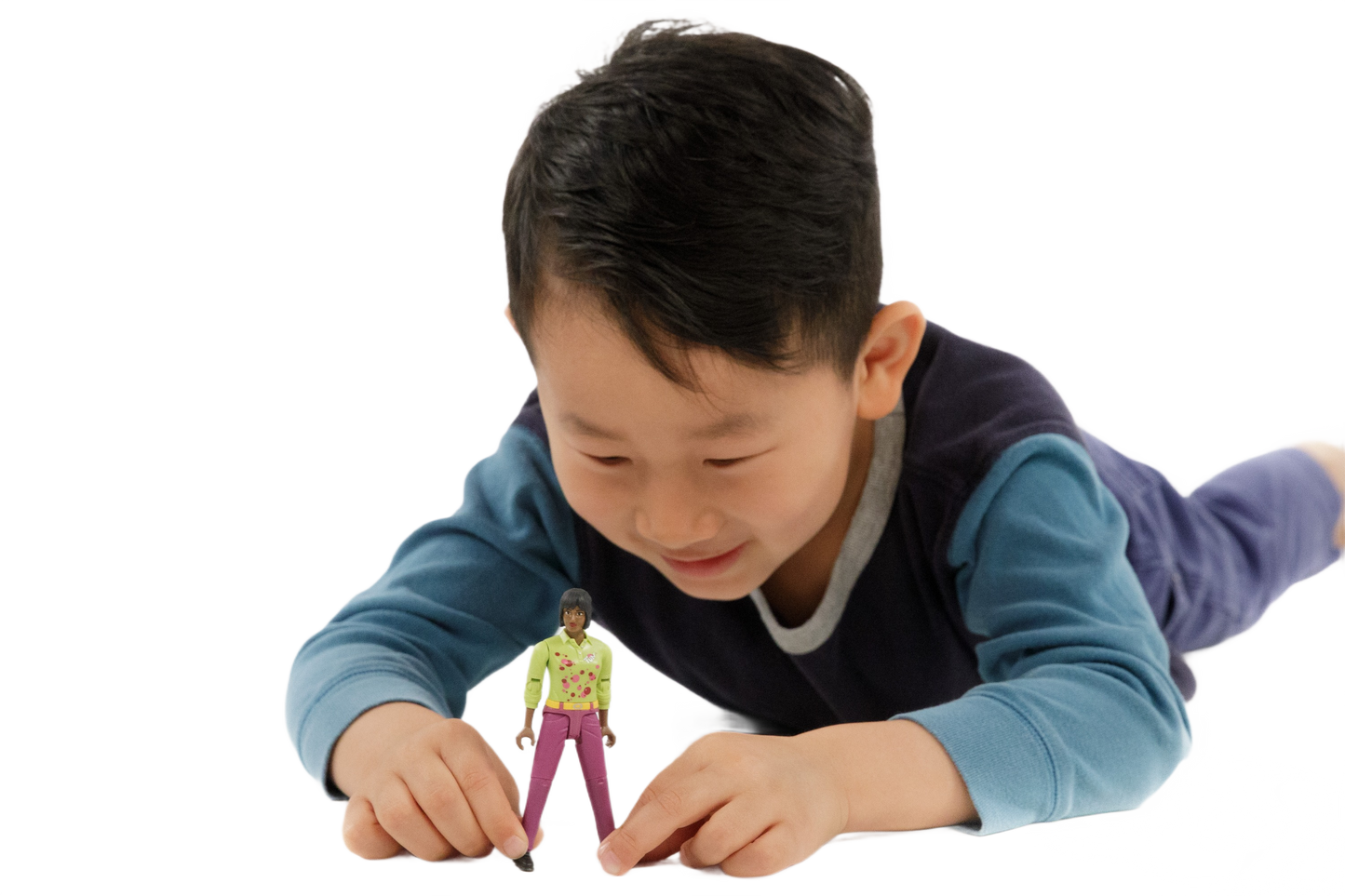 Child in blue and navy shirt playing with a medium skin tone toy woman figure wearing pink pants and a yellow top