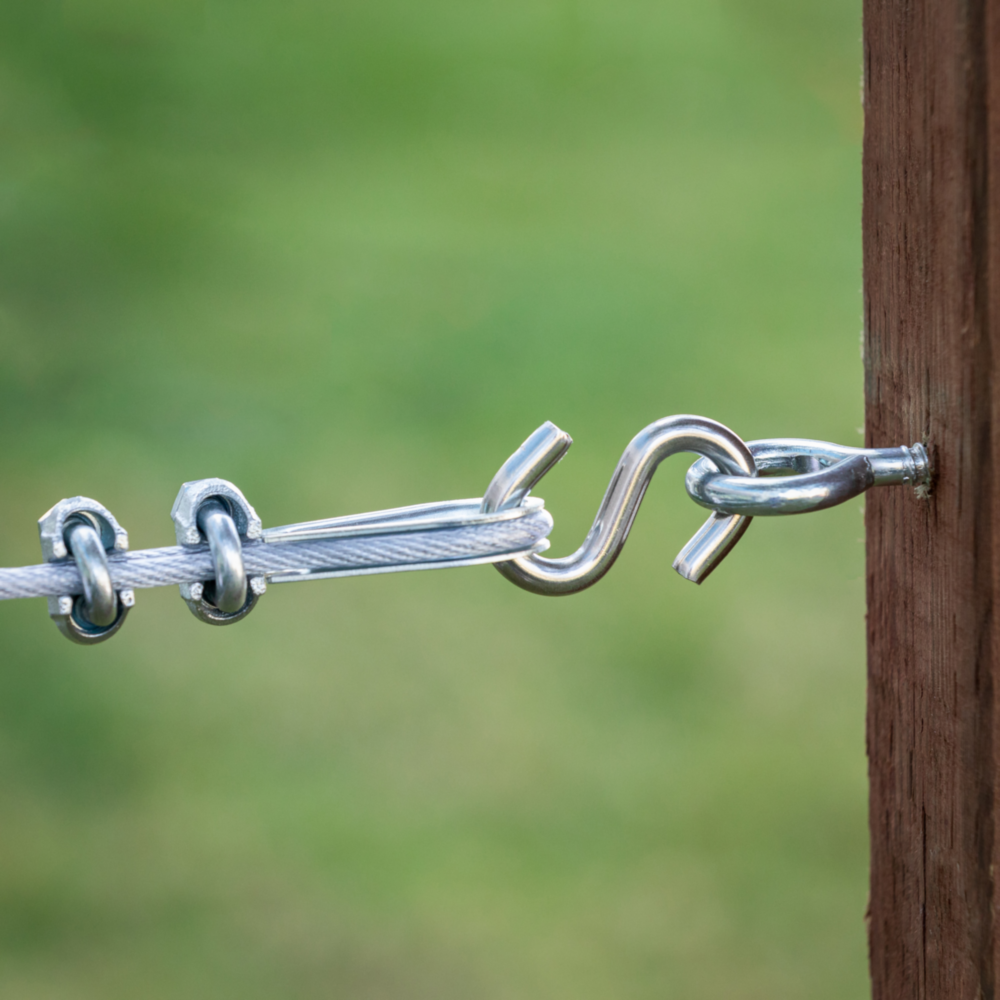 Zinc heavy-duty open S hook connecting cable wire rope to metal eye secured in wooden post for hardware projects