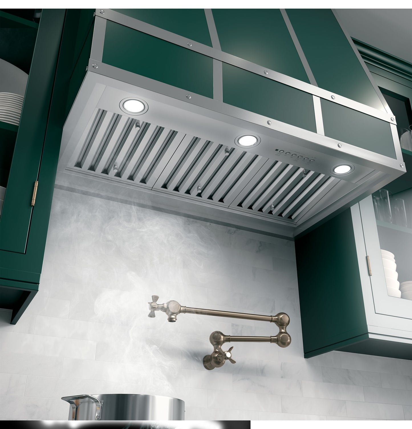 Custom stainless steel range hood insert with dimmable LED lights, mounted above a stove with green cabinetry and pot filler faucet