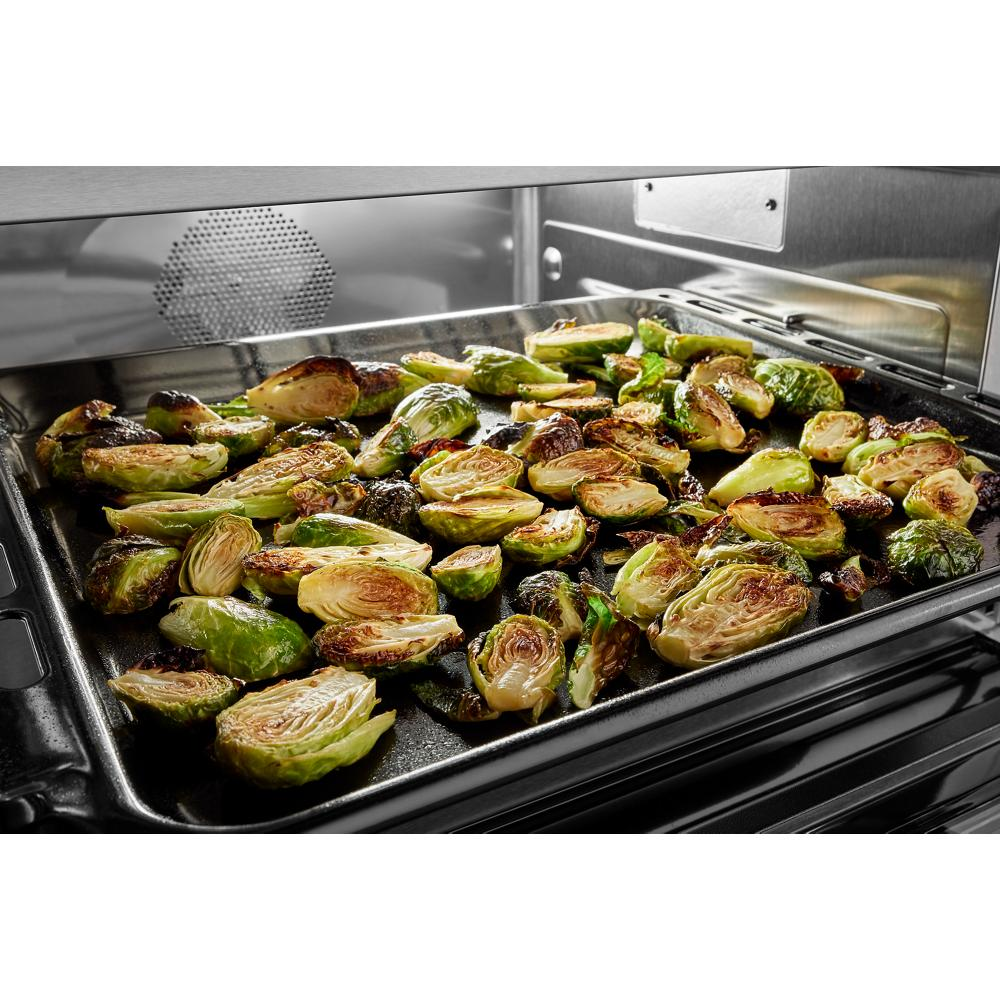 Roasted Brussels sprouts on a black baking tray inside a stainless steel smart electric wall oven from KitchenAid collection