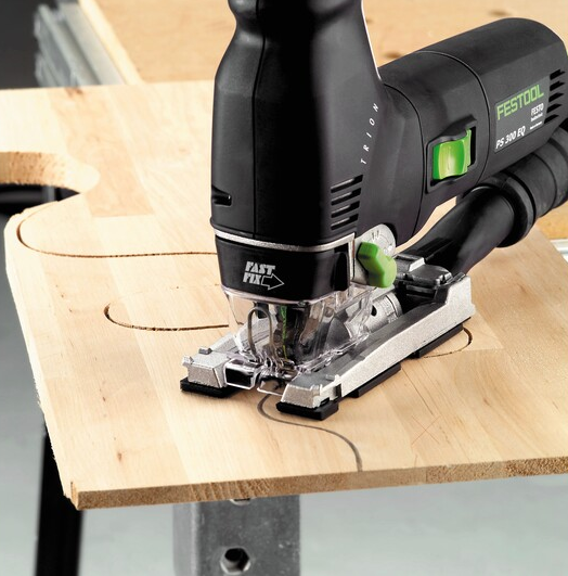 Black and green Festool jigsaw cutting curved pattern into light wood panel for tools and home improvement projects