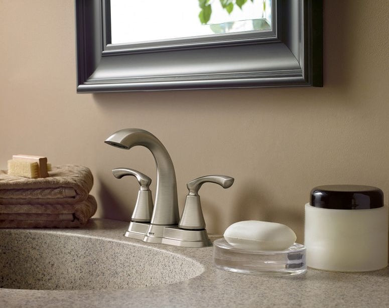 Brushed nickel two-handle high arc faucet installed on bathroom sink with towels and soap dish nearby